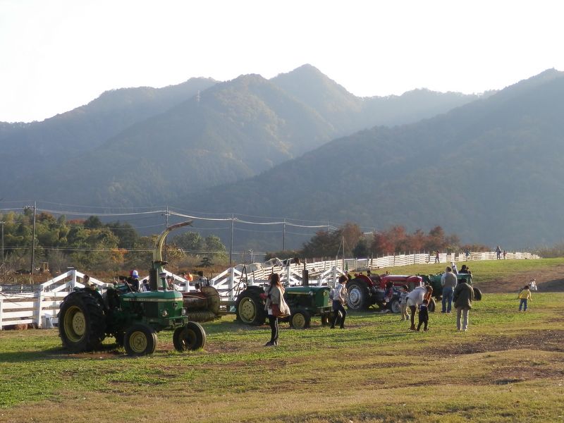 仏果山を背に、牧場の退役兵トラクターと遊ぶ子供ら